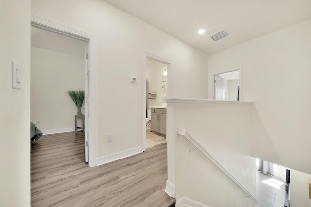 corridor with light wood-type flooring, visible vents, an upstairs landing, recessed lighting, and baseboards