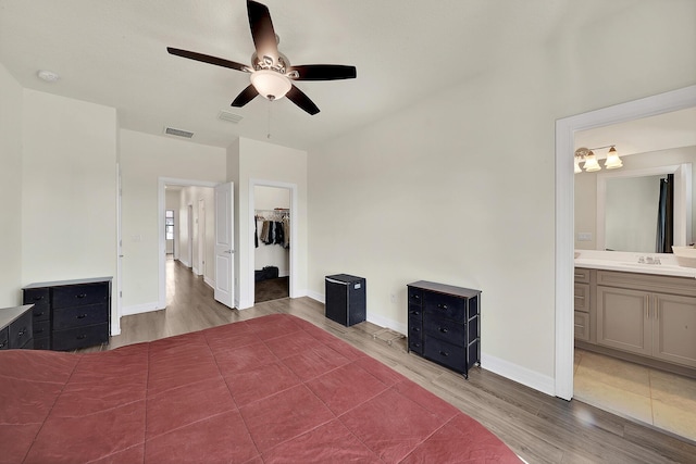 unfurnished bedroom featuring visible vents, ensuite bathroom, and wood finished floors