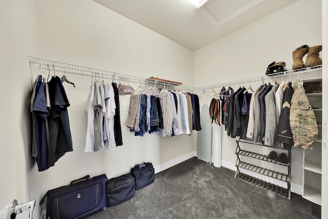 walk in closet featuring attic access and dark carpet