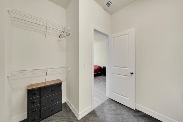 spacious closet with visible vents and dark carpet