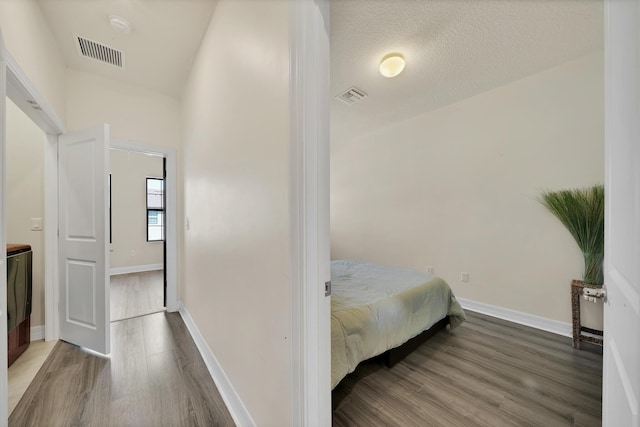 bedroom featuring visible vents, baseboards, and wood finished floors