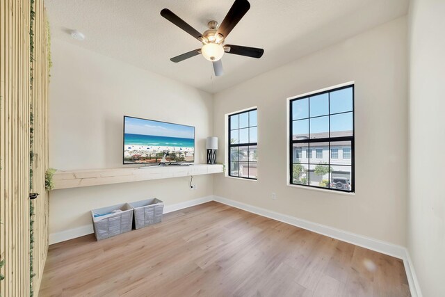 interior space featuring ceiling fan, baseboards, and wood finished floors