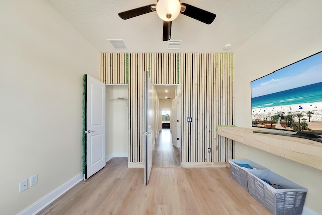 unfurnished room featuring a ceiling fan, wood finished floors, visible vents, and baseboards