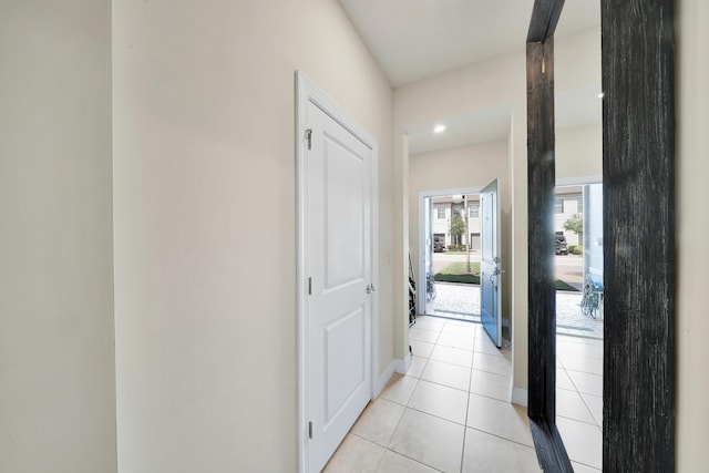 corridor featuring light tile patterned floors and baseboards