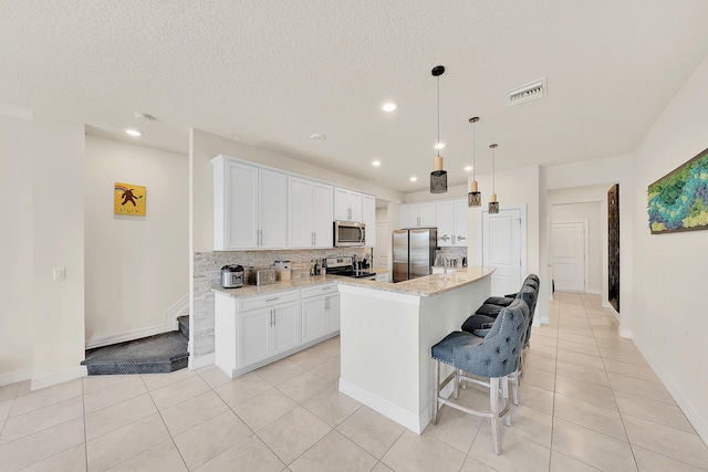 kitchen featuring visible vents, white cabinets, and stainless steel appliances