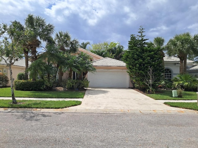 view of front facade with concrete driveway, a tile roof, an attached garage, a front lawn, and stucco siding