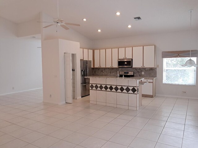 kitchen with tasteful backsplash, visible vents, a kitchen island, stainless steel appliances, and light tile patterned flooring