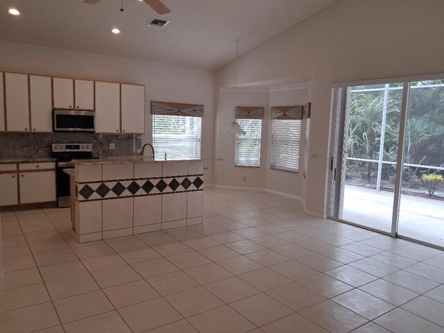 kitchen with lofted ceiling, ceiling fan, stainless steel appliances, visible vents, and backsplash