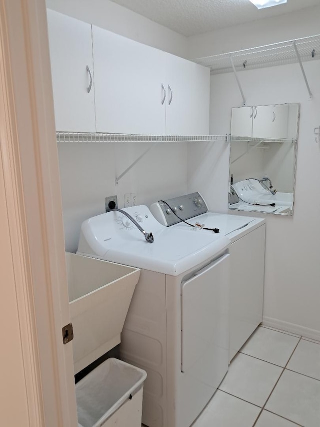 laundry room featuring cabinet space, baseboards, washer and clothes dryer, a sink, and light tile patterned flooring