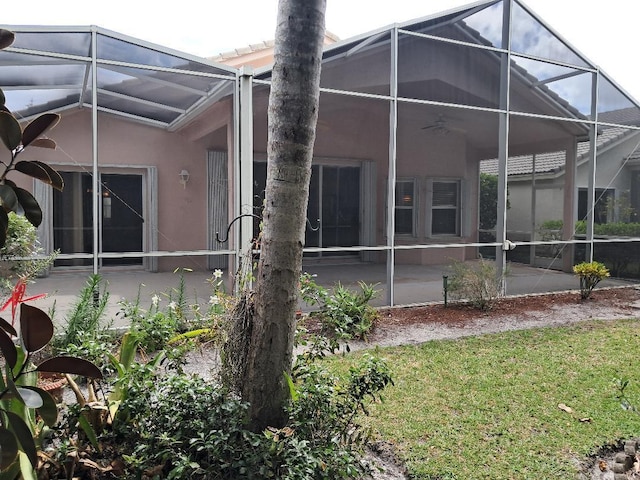 7260 SE Magellan Ln, Stuart, FL 34997 - back of house with a patio area, glass enclosure, stucco siding, and a lawn