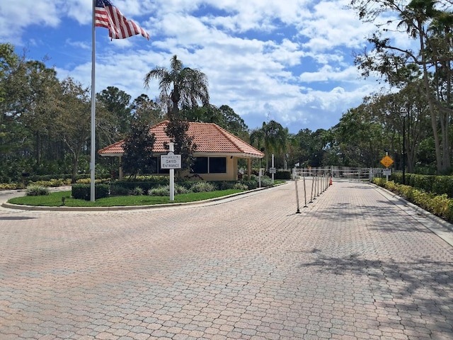 view of street featuring traffic signs, a gate, curbs, and a gated entry