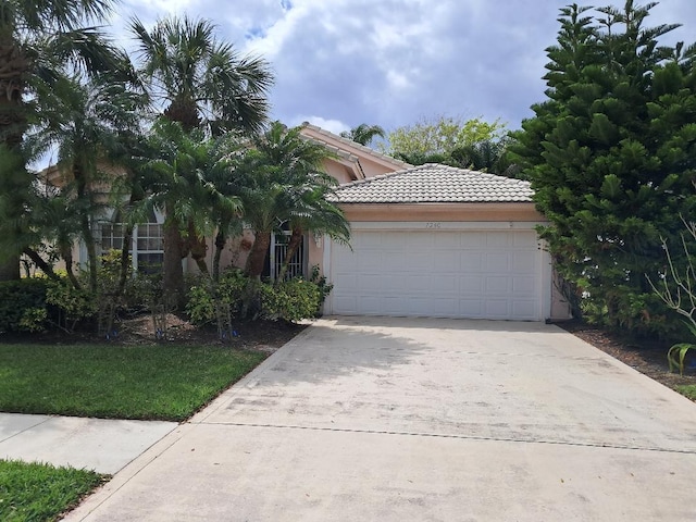 view of front of home featuring driveway, a tiled roof, a garage, and stucco siding