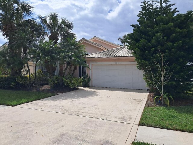 view of front of property featuring a garage, a tiled roof, concrete driveway, and stucco siding