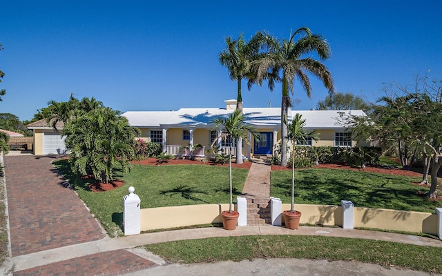 ranch-style home with a garage, covered porch, fence, decorative driveway, and a front lawn