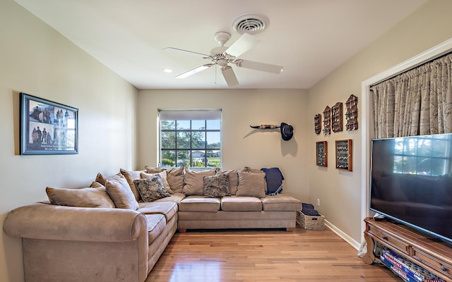 living room featuring baseboards, light wood-style flooring, visible vents, and a ceiling fan