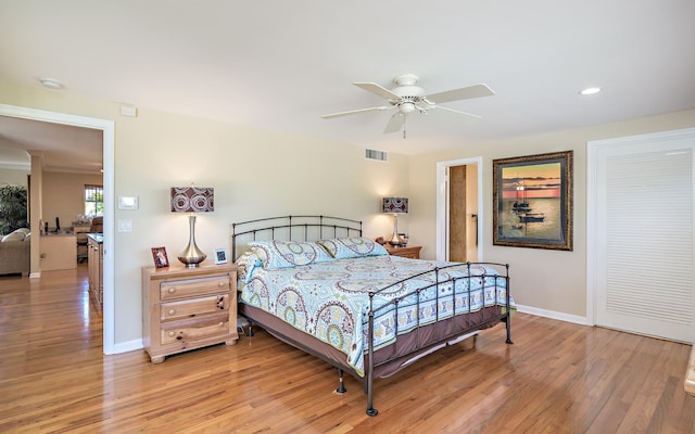 bedroom featuring ceiling fan, light wood finished floors, visible vents, and baseboards