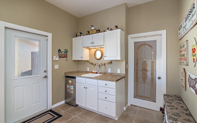 kitchen featuring white cabinetry, a sink, dishwasher, and light tile patterned flooring