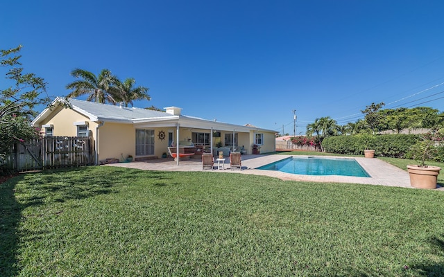 rear view of house with a fenced in pool, a lawn, a fenced backyard, a patio area, and stucco siding