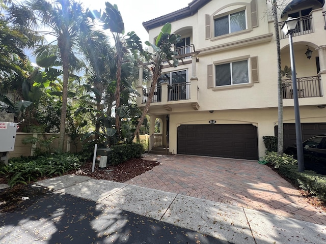 multi unit property featuring an attached garage, decorative driveway, and stucco siding