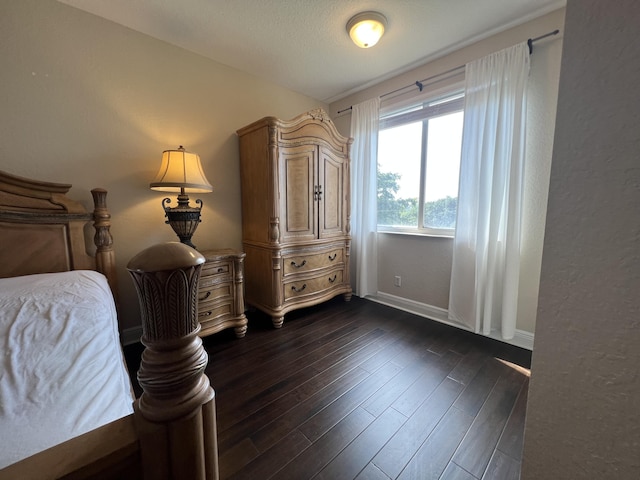 bedroom with dark wood-type flooring and baseboards