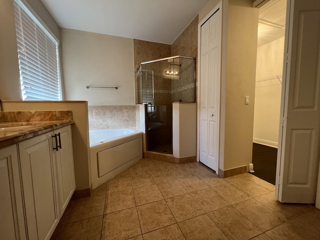 bathroom with a garden tub, a stall shower, vanity, baseboards, and tile patterned floors