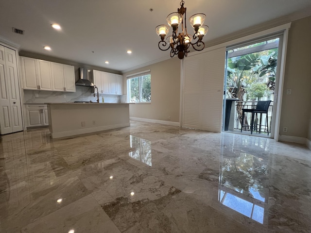 kitchen featuring marble finish floor, crown molding, wall chimney range hood, and baseboards