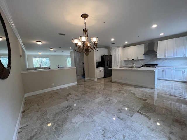 kitchen with wall chimney range hood, ornamental molding, marble finish floor, and black fridge