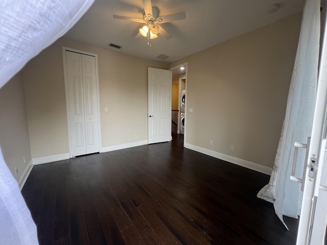 interior space featuring dark wood-style floors, ceiling fan, visible vents, and baseboards