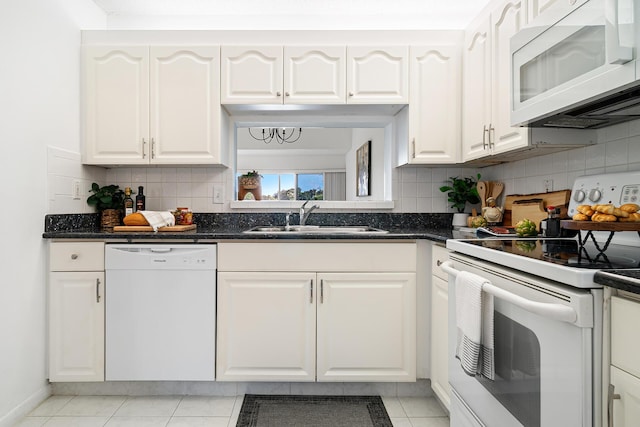 kitchen with white appliances, decorative backsplash, a sink, and white cabinets