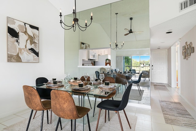 dining area with visible vents, light tile patterned flooring, high vaulted ceiling, baseboards, and ceiling fan with notable chandelier