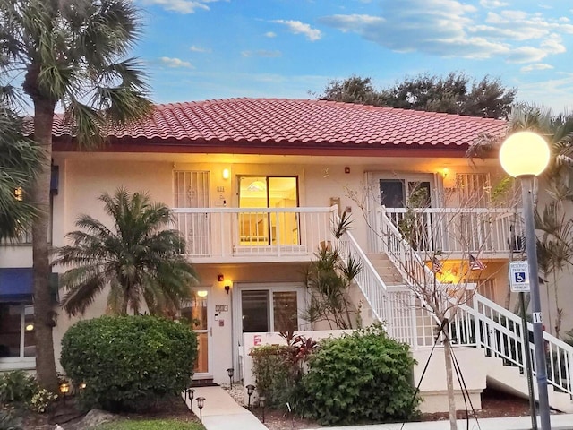 view of front of property with a tiled roof, stairway, and stucco siding