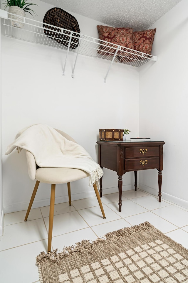 interior space featuring light tile patterned floors, a textured ceiling, and baseboards