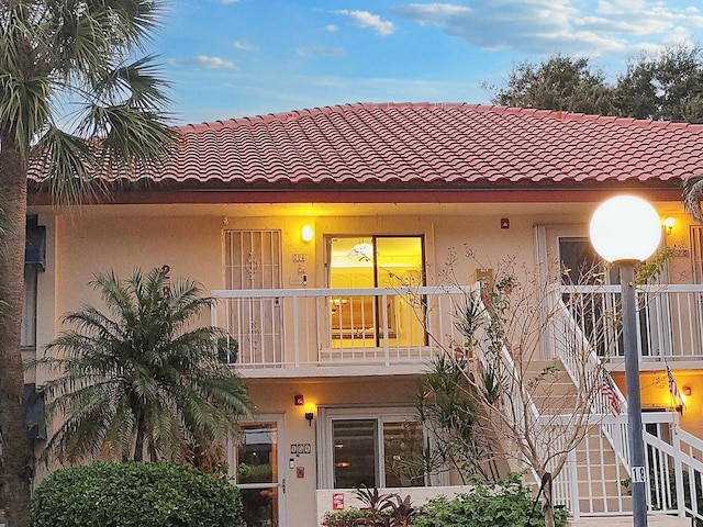 view of front of home featuring stairway, a tile roof, and stucco siding