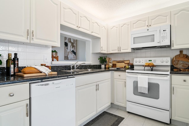 kitchen featuring light tile patterned floors, white appliances, a sink, and white cabinetry