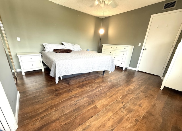 bedroom featuring visible vents, baseboards, dark wood-type flooring, and a textured ceiling