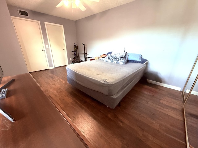 bedroom with visible vents, ceiling fan, baseboards, and dark wood-style flooring