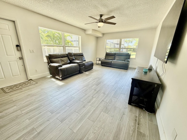 living area featuring baseboards, wood finished floors, a textured ceiling, and ceiling fan