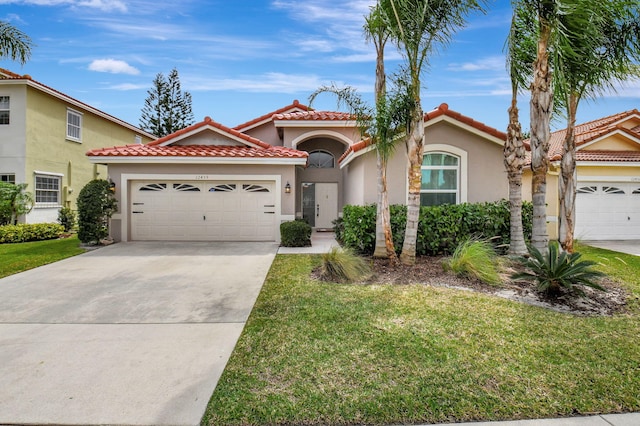 mediterranean / spanish home featuring stucco siding, an attached garage, a front yard, driveway, and a tiled roof