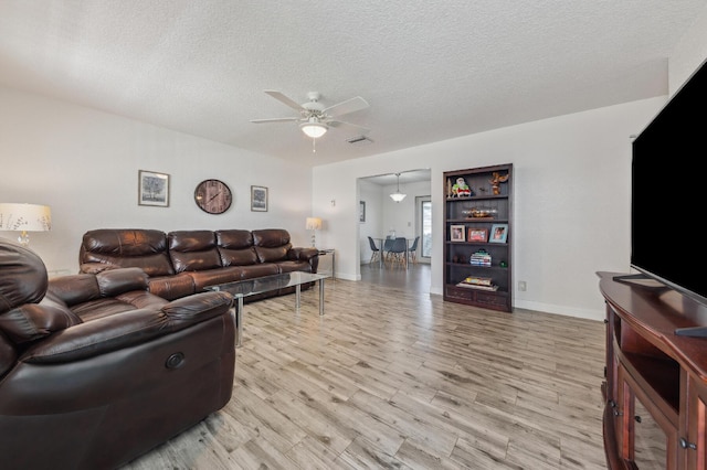 living room with light wood finished floors, visible vents, ceiling fan, a textured ceiling, and baseboards