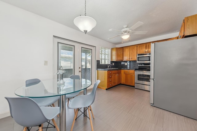 kitchen with french doors, brown cabinets, decorative backsplash, appliances with stainless steel finishes, and a sink