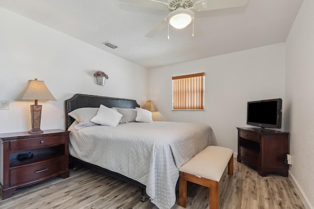 bedroom with baseboards, visible vents, ceiling fan, and light wood finished floors