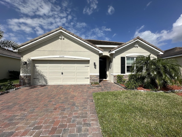 view of front facade featuring decorative driveway, a tile roof, stucco siding, an attached garage, and stone siding