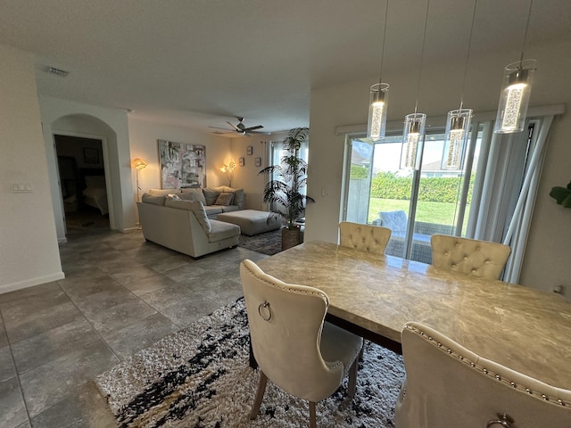 dining space featuring arched walkways, ceiling fan, visible vents, and baseboards