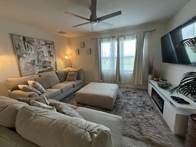 carpeted living room with a textured ceiling, visible vents, and a ceiling fan