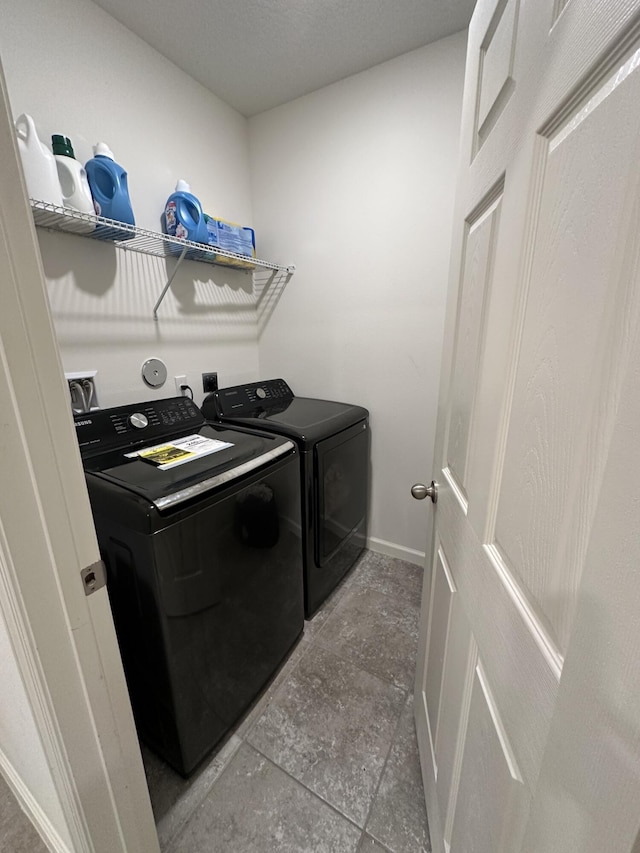 laundry room featuring laundry area, baseboards, a textured ceiling, and washing machine and clothes dryer