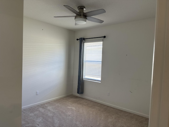 spare room with baseboards, ceiling fan, a textured ceiling, and light colored carpet