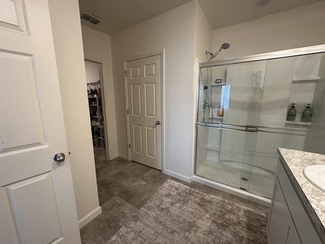 full bathroom featuring a stall shower, vanity, visible vents, and baseboards