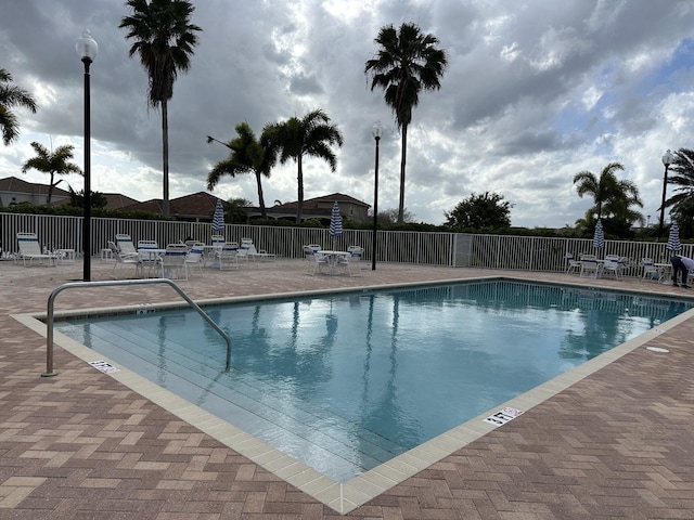 community pool with a patio and fence