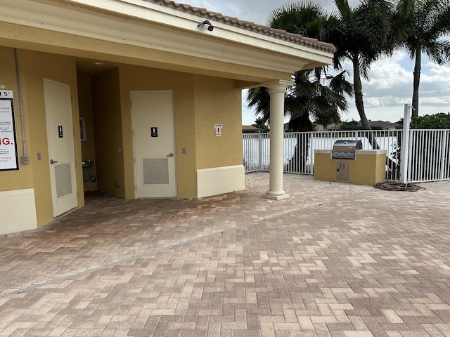 view of patio with area for grilling, visible vents, and fence
