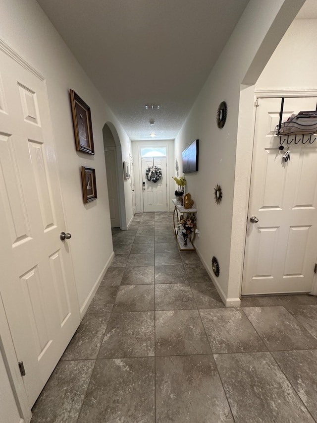 hallway featuring arched walkways, visible vents, and baseboards